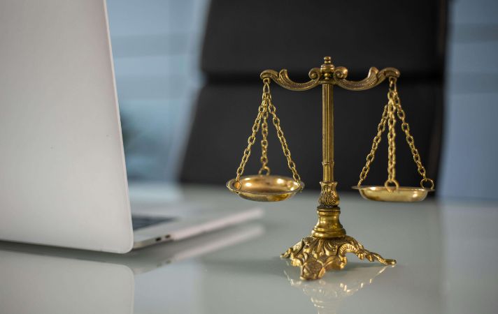 Golden legal scales on a table next to an open laptop.